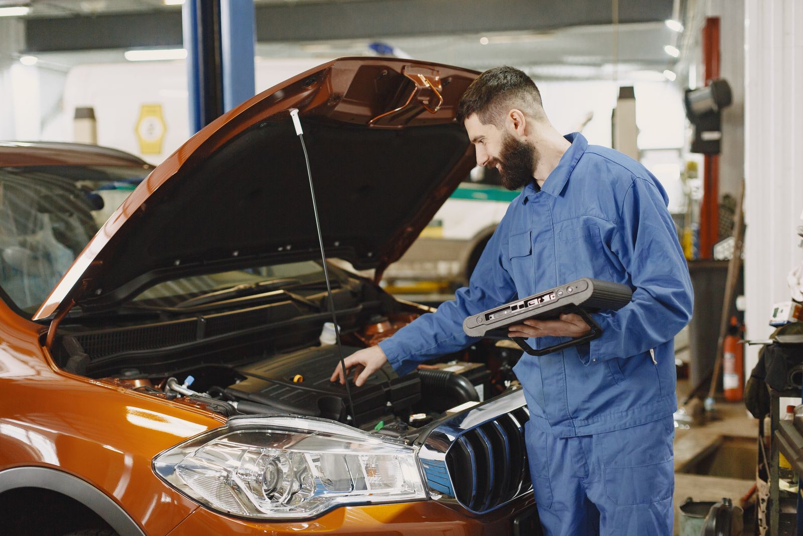 Kaput altında motor sensörlerini kontrol eden teknisyen